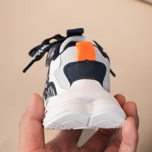 Détail du talon de basket enfant avec cuir bleu marine, mesh blanc et languette orange
