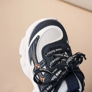 Gros plan sur baskets enfant en maille bleu marine avec détails orange vifs