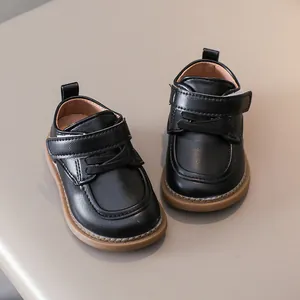 Detail view of black toddler leather shoes with hook-and-loop closure and non-slip brown sole