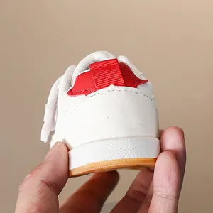 Dettaglio di scarpe sportive bianche per bambini con linguetta rossa e suola in gomma antiscivolo
