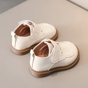 Detail view of cream toddler shoes featuring non-slip gum sole and hook-and-loop closure