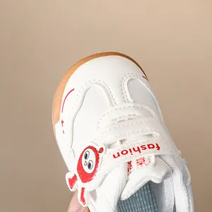 Dettaglio scarpe sportive bianche per bambini con accenti rossi e suola in gomma morbida