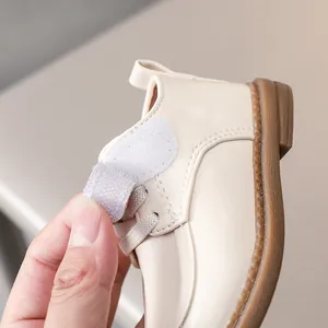 Detail view of cream white baby shoe featuring hook-and-loop closure and flexible rubber sole