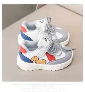 Detail view of kids leather sneakers showing gray toe and orange M letter appliqué