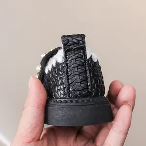 Detailansicht der Ferse vom schwarzen Kinder-Flechtschuh mit weißem Pelz und Perle
