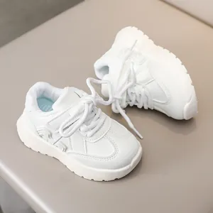 Detail of white leather kids sneakers with velcro straps and anti-slip thick soles