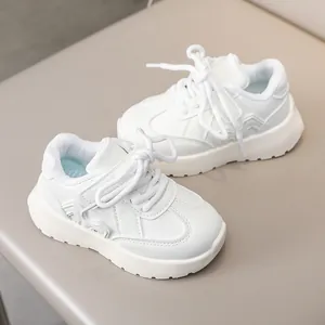 Close-up of white leather kids sneakers with anti-slip thick soles and lace-up design