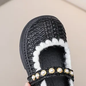 Detail von schwarzen geflochtenen Mary Janes mit Perlriemen und weißem Wellenrand