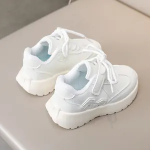 Detail of white kids sneakers with hook-and-loop straps and premium faux leather finish
