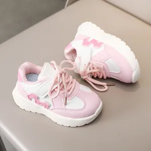 Detail of pink and white children's sneakers with velcro strap and letter M design