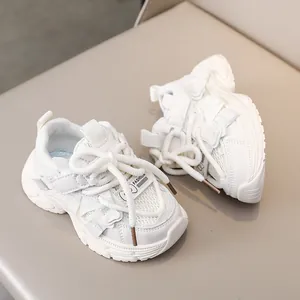 Detail of girls' white sneakers with mesh fabric, thick laces, and 3D bear decor