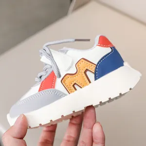 Detail view of children's color-block sneakers with M-logo design and velcro strap