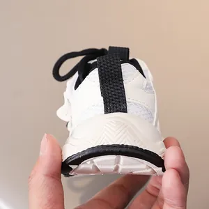 Detailed macro view of white kids' sneaker showing breathable mesh and heel pull tab