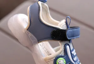 Detail of blue mesh kids sandals showing velcro strap and green spider logo on the side