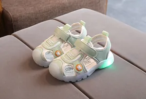 Close-up of kids light-up sandals featuring green LED soles and spider pattern details