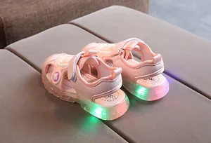 Detailed view of pink LED glowing soles on kids sandals with secure velcro straps