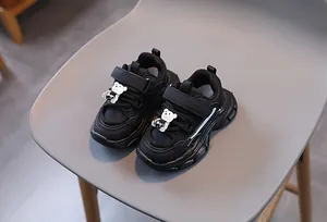Gros plan de chaussures de sport noires pour enfants avec Velcro et détail d'ours
