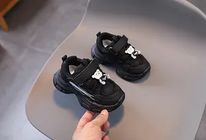 Détail de chaussures de sport noires pour filles avec velcro et décoration ours mignon