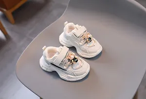 Détail de baskets beige pour enfants en cuir avec une figurine d'ours 3D et bande velcro