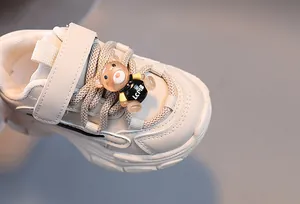 Détail de baskets beige pour enfants avec semelles chunky et ornement d'ours en 3D