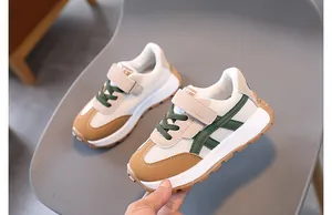 Close-up of kids casual sneaker featuring mesh upper, velcro strap, and green side stripes