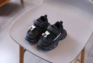 Détail de baskets noires pour enfants avec scratch et accessoire ours en 3D