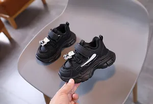 Détail de baskets noires pour enfants avec breloques d'ours et semelles antidérapantes