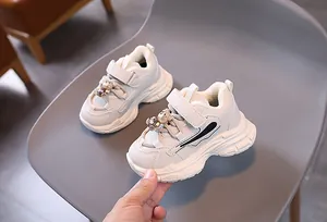 Détail de baskets enfants crème avec breloque ours en 3D et doublure en polaire douce