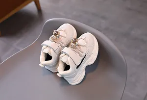 Vue détaillée des baskets crème pour enfants avec velcro et breloque ourson adorable