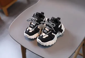 Detail of kids athletic dad sneakers in black and white leather with chunky wave sole