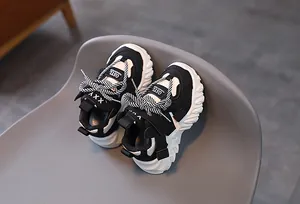 Detail of kids' black and white chunky sneakers with mesh texture and strap closure