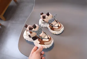 Close-up of children chunky sneakers with brown patchwork and durable velcro strap