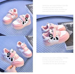 Detail of pink and white baby sneakers with cartoon panda and velcro straps on glass tray
