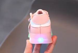 Close-up of baby girl sneakers with blue LED light-up sole in pink and white