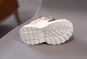 Macro view of white thick sole with anti-slip pattern and size number 23 on kids sneakers