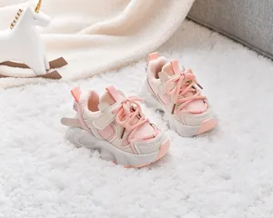 Detail of pink and beige kids' warm fleece-lined sneakers on soft white plush rug