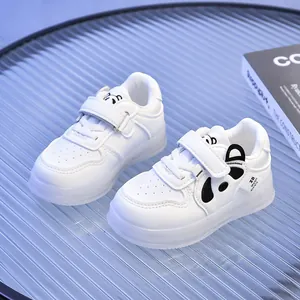 Detail of white toddler sneaker featuring a cartoon panda design and velcro strap closure