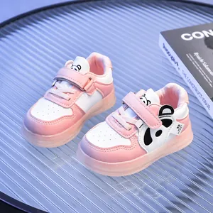 Detail of pink and white baby sneakers with panda cartoon design and velcro strap
