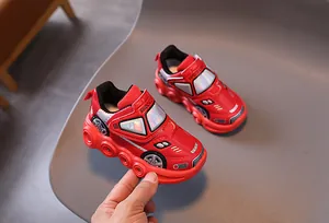 Detail of red cartoon car-shaped kids sneakers with velcro strap and shock light text