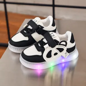 Detail of LED light-up sole on kids' sneakers with cute panda motif and velcro strap