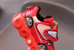 Detail of red racing-themed LED kids sneaker showing wheel print and velcro strap