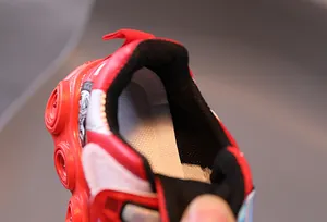 Detail shot of boys LED light-up shoes with red pull tab and breathable honeycomb lining