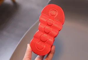 Detail view of red children's sneaker sole featuring non-slip rubber texture and size 23