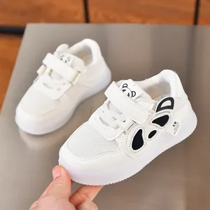 Close-up of white toddler sneakers with black panda design and velcro strap detail