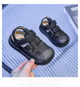 Detail of kids black closed-toe mesh sandals featuring leather straps and velcro closure