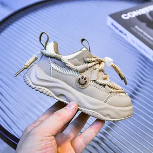 Détail de baskets beige pour enfants avec mesh respirant et écusson visage souriant