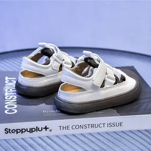 Detail of children's white leather sandals with dual Velcro straps and thick brown soles