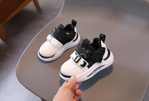Detail of kids sneakers with black and white synthetic leather upper and buckled straps