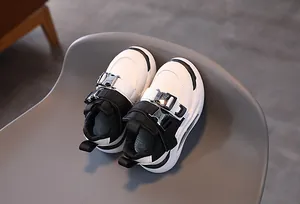 Detail of kids black and white sneakers featuring metal buckles and thick anti-slip soles