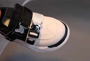 Detail of children's sneaker showing leather texture, velcro strap and metal buckle